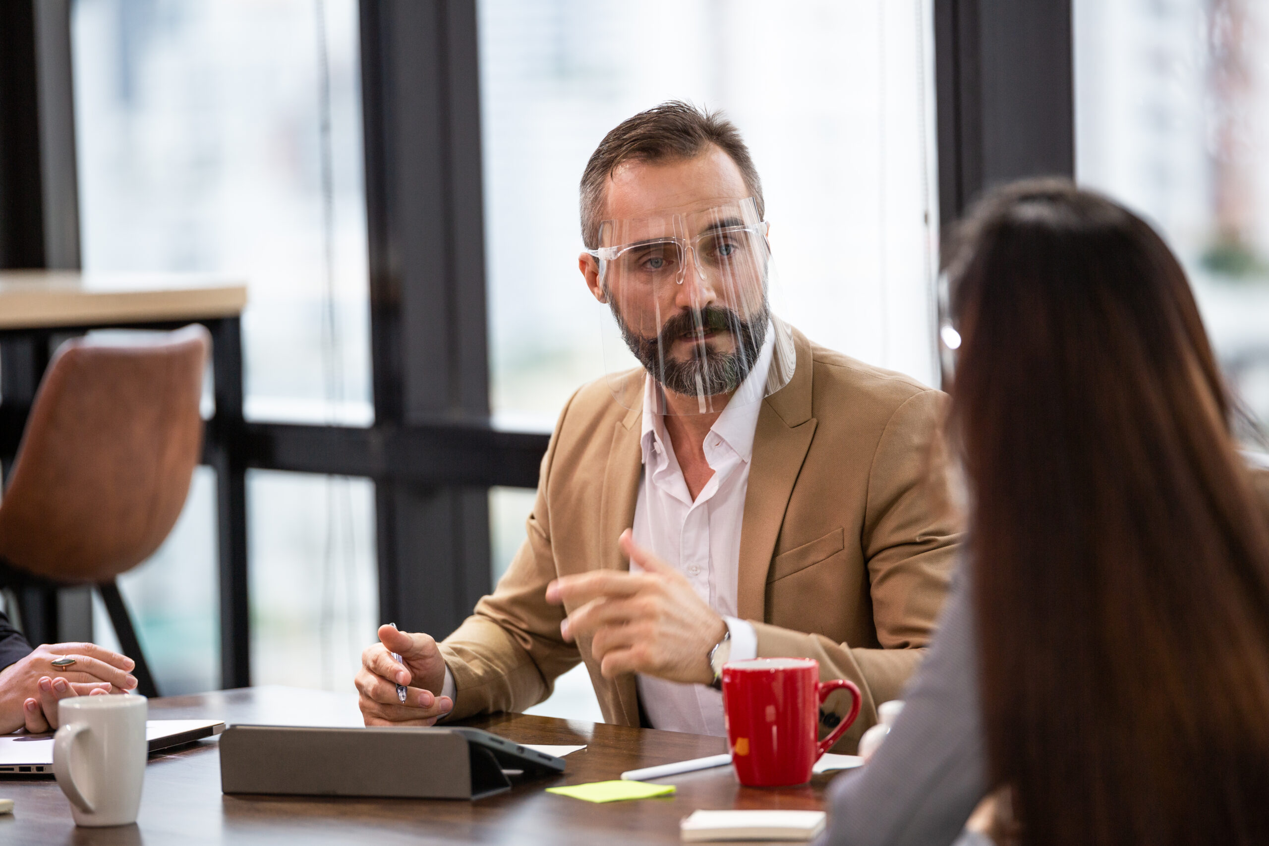 Caucasian business man wearing face shield discussing and brainstorming with team in co-working space or office meeting room. partnership people working together, project dealing with customer